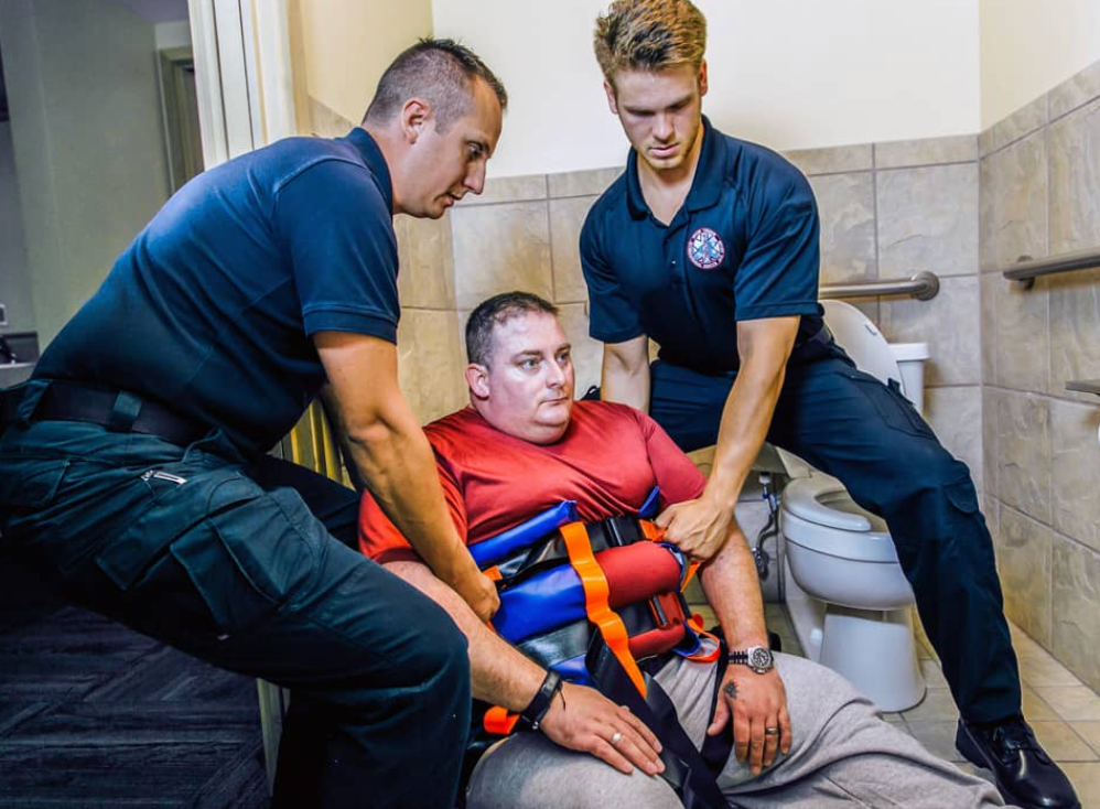 Binder Lift being used by firefighters in a confined space to safely lift a patient from the confined space of a bathroom. PN: SV-BL